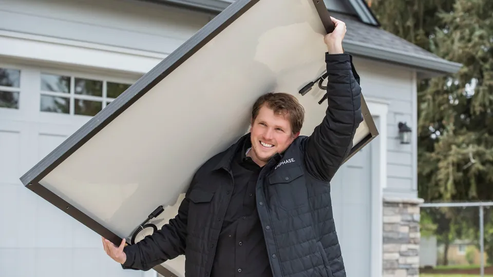 Energy Solutions installer carrying a solar panel on his shoulder