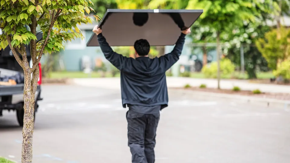 Energy Solutions installer carrying a solar panel overhead