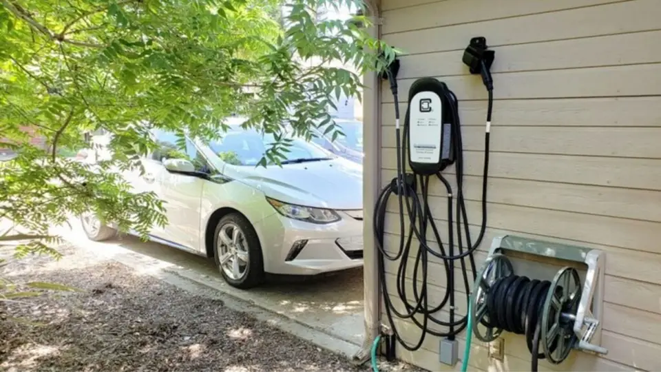 Clipper Creek EV charger on side of home with car in driveway