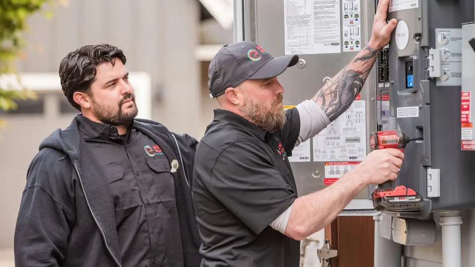Two Energy Solutions electricians at a home's meter and electrical panel