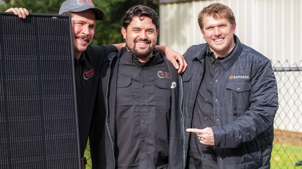 Three Energy Solutions crew members holding a solar panel