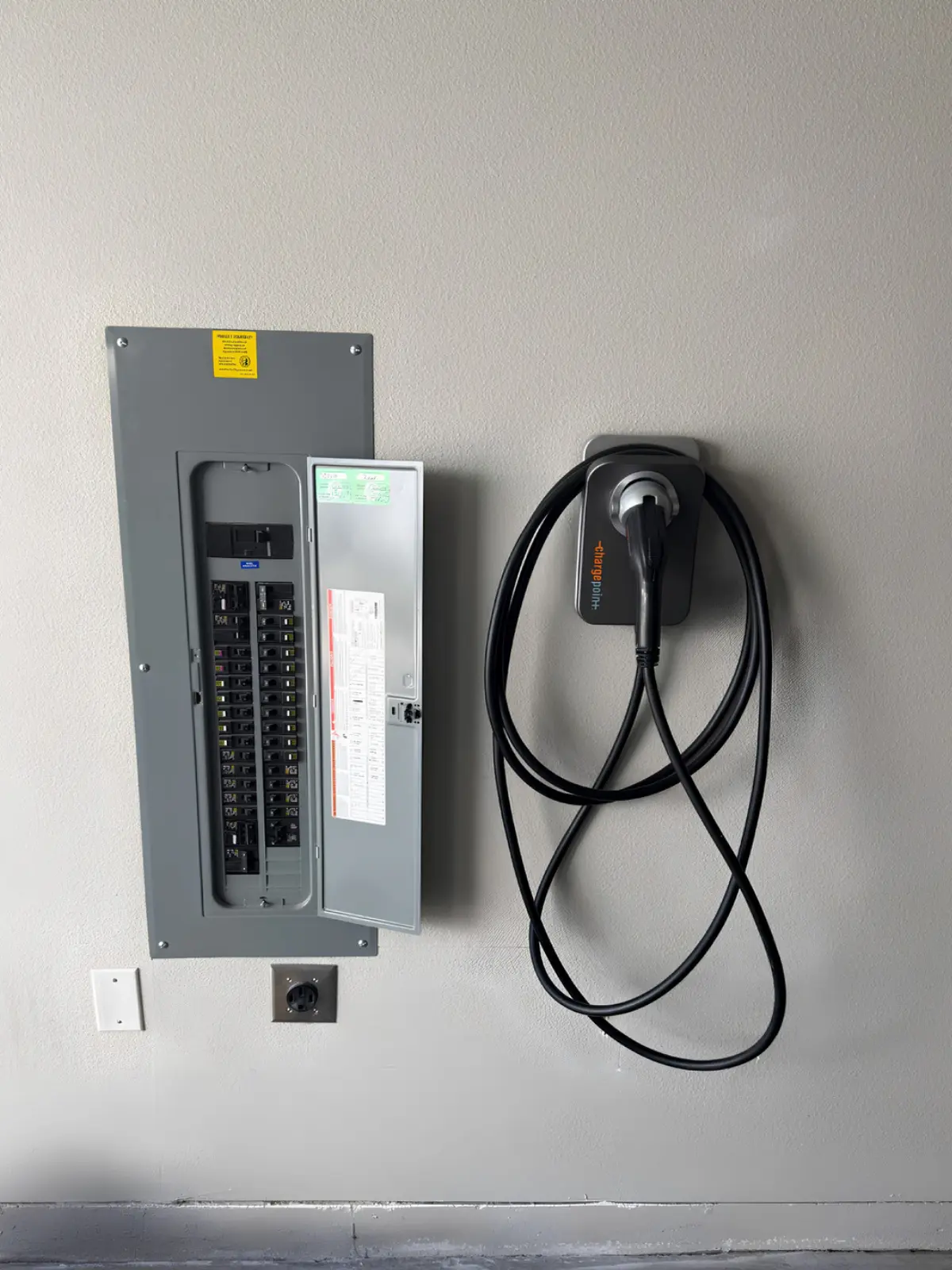 Wall-mounted ChargePoint EV charger beside an electrical panel.