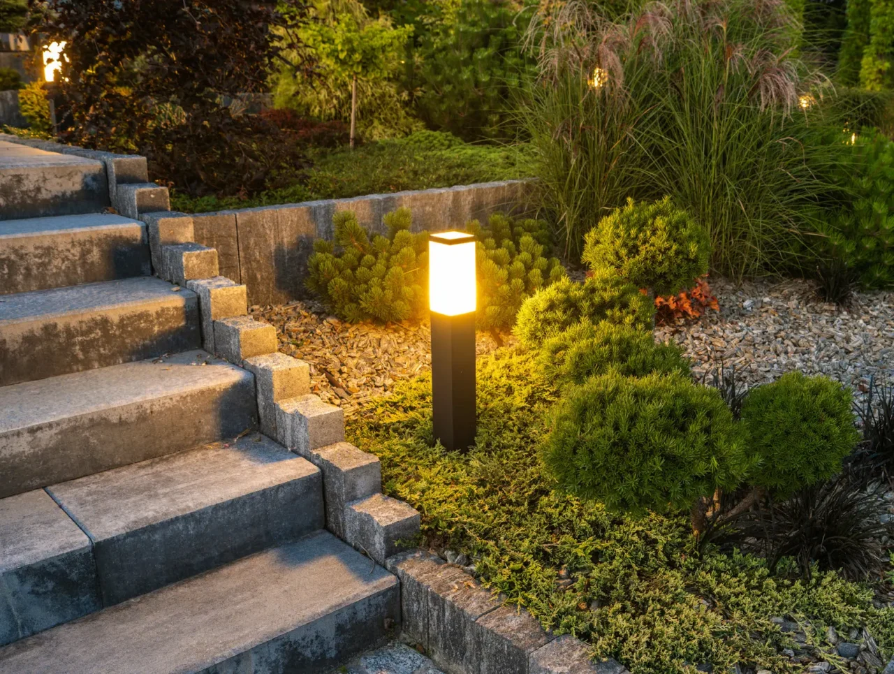 Illuminated garden path with stone steps at dusk.