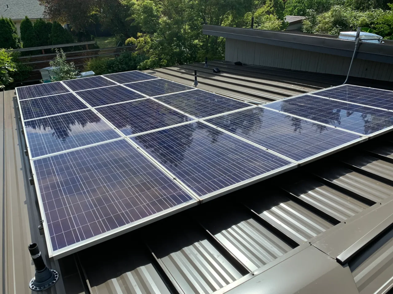 New Solar Installation Solar panels gleam blue on metal roof, sunny day.