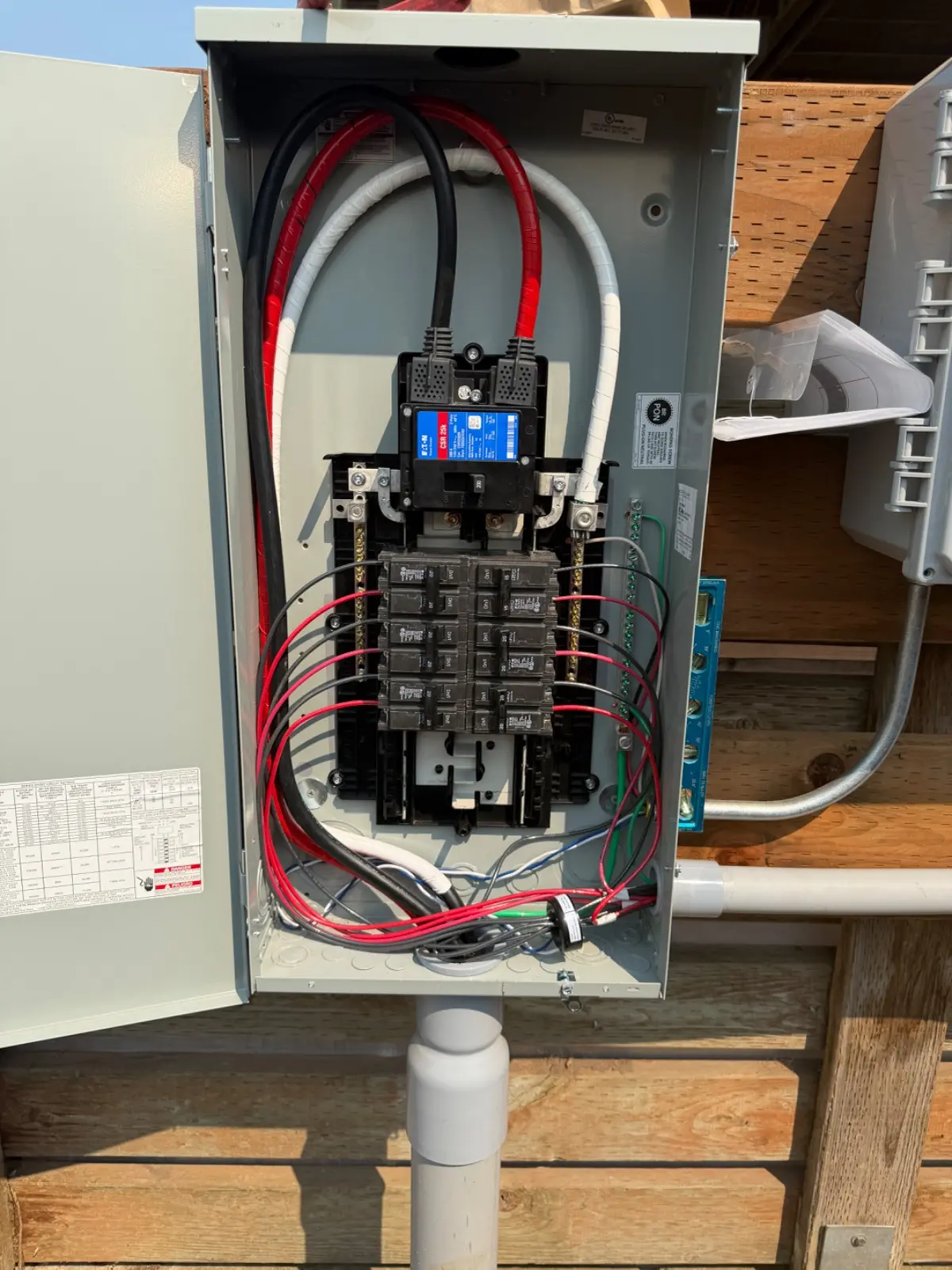 Open electrical breaker panel with main disconnect, circuit breakers, and exposed wiring.