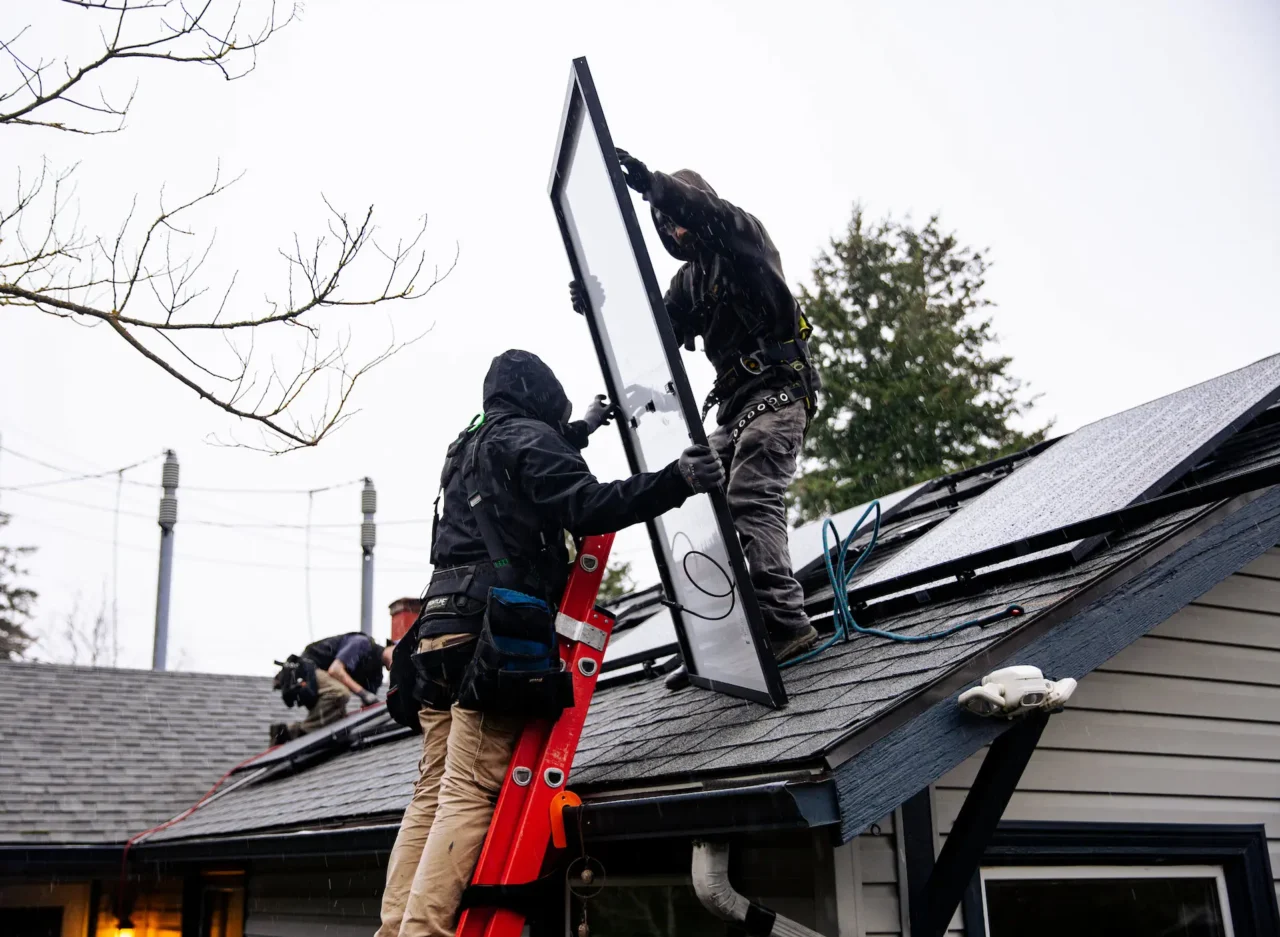 Solar Removal & Reinstall Workers install solar panels on a rooftop in rain.