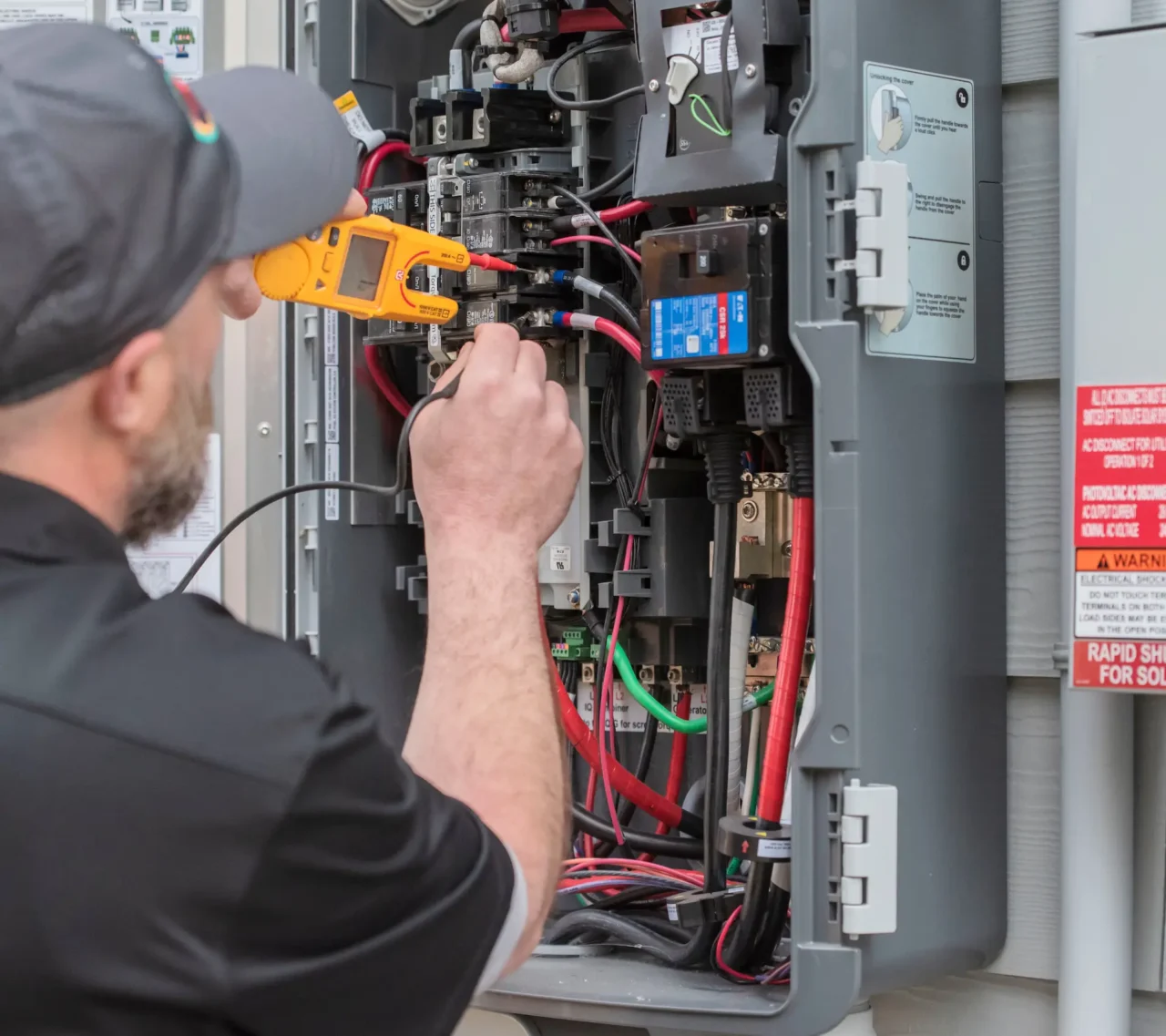Technician testing electrical panel with multimeter.