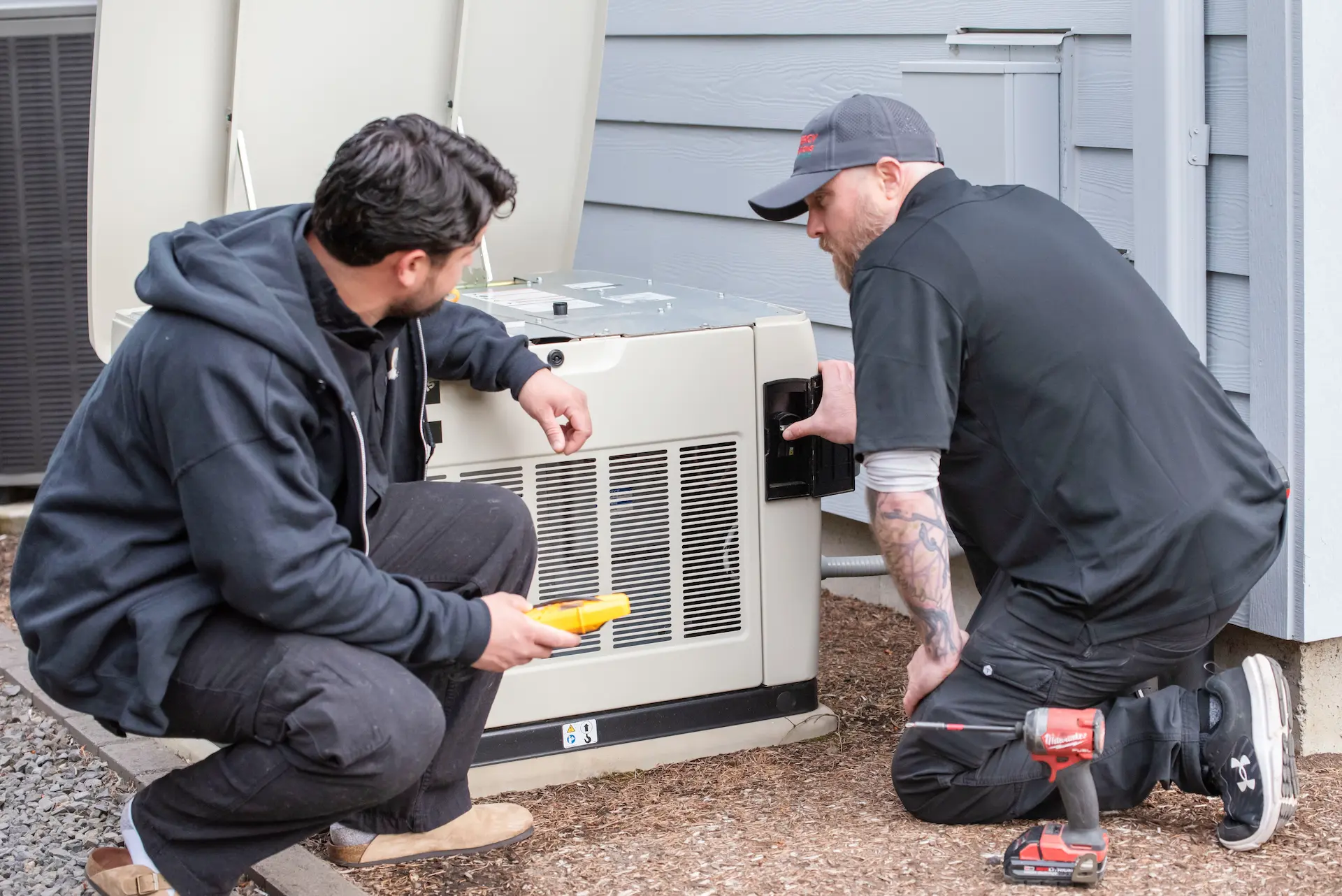 Two technicians inspecting a residential standby generator.