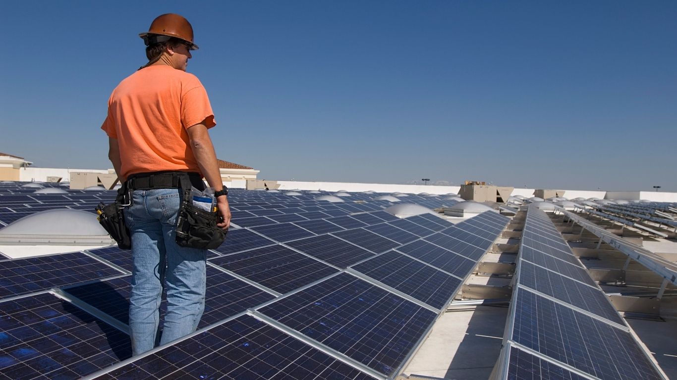 man walking on roof of commercial PV system